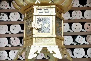 <p>Another lantern near a wall of prayer signs in the shape of hand-mirrors</p>