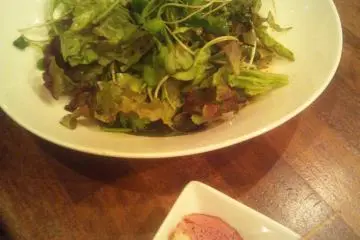 Fresh green lettuce with vinaigrette and the "otoshi" (some might say "extortion") plate
