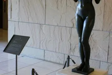 <p>She greets visitors as they enter the main entrance after ascending very long escalators or staircases.</p>