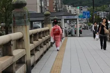 Here, a traditional entertainer known as a Maiko can be seen crossing the Gojo Oohashi Bridge, which extends over the secondary branch of the Kamogawa River