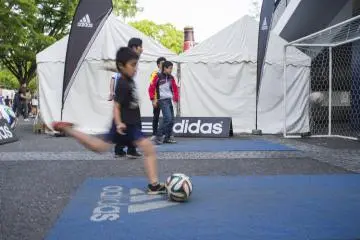 A young boy trying to knock pins with his football skills.