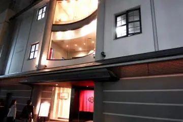 Restaurant 'Beef MIKAKU' and 'MIKAKU 2nd' viewed from the street. A young couple is looking up at the building trying to decide whether to go in or not...