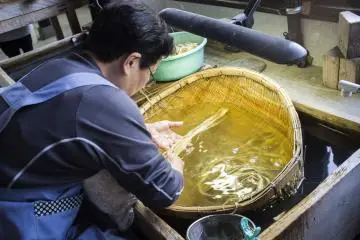 한 할머니가 와시를 만드는데 사용되는 뽕나무 껍질을 열심히 닦고 있다.