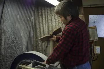 <p>Hideo Takamura&nbsp;hitting the carving whetstone to ensure more friction during the buffering process.</p>