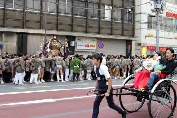 <p>The festival spilled onto the road as the "mikoshi" were traveling back home. While they were on the road the normal life was going on, including cars and rickshaws.&nbsp;</p>