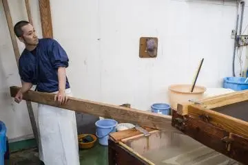 많은 와시 장인들 중 한 명이 거대한 스크린을 지탱하기 위해 판자를 사용했다