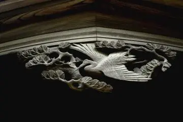 <p>A carving of a crane flying over pine branches</p>