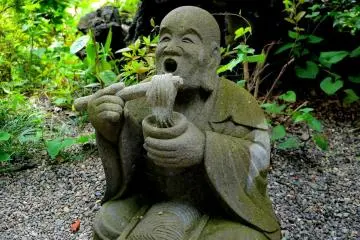 <p>Statue of monk eating noodles</p>