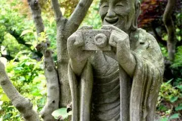 <p>Statue of monk taking a photo</p>