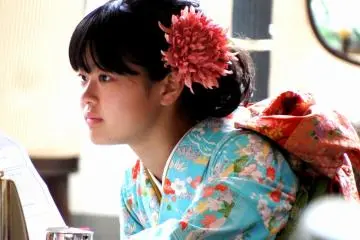 <p>Lovely flower decorating her hair goes well with the blue color of her kimono and matches the color of the Obi sash. Perfect!</p>