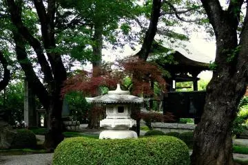 <p>Stone lantern behind a manicured fence</p>