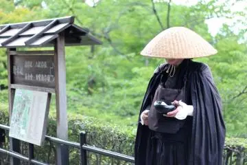<p>นักบวชนิกายเซนยืนขอบริจาคทานอย่างสงบที่มุมหนึ่งในบริเวณวัด</p>
