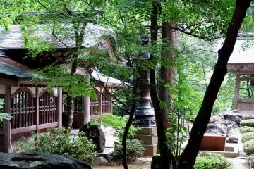 <p>Bronze lantern standing in the midst of a courtyard surrounded by trees</p>