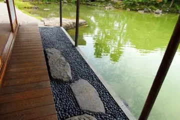 Di luar beranda, batu untuk injak di atas batu bulat dan kolam