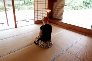 Wanita Barat sedang duduk di atas tikar tatami dan menikmati pemandangan