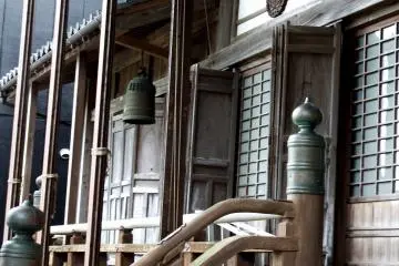 <p>Front corridor of the main temple building and a bronze bell hanging from the ceiling</p>