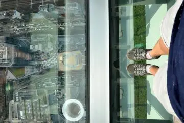 <p>Facing West, one stands on a glass panel that allows you to look beneath</p>