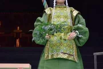 <p>A shrine maiden wearing beautiful&nbsp;attire performs kagura with green sprig</p>