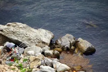 <p>Someone enjoying fishing from the rocky shore</p>
