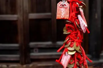 <p>Small charms and five yen coins woven into a decorative rope</p>