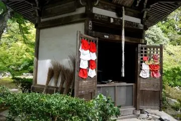<p>Red and white aprons hang on the doors of this shrine, and brooms lean against the side... I wonder if it is a shrine to cleanliness?</p>