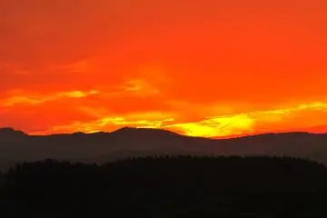 Lors du coucher de soleil, émerveillés, les spectateurs restent bouche bée devant le rouge flamboyant du ciel