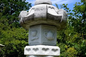 <p>Hearts and a teapot decorate this stone lantern... could it be it an Alice in Wonderland theme?</p>