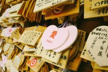 Wooden prayer boards, one of them a pair of pink hearts, presumably a prayer from a couple
