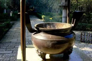 <p>Incense sticks stand in a cauldron full of sand</p>