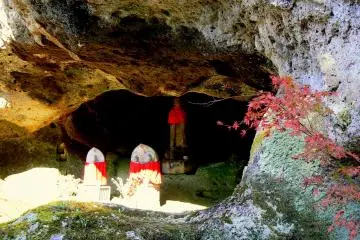 <p>Statues with red aprons in the entrance to one of the caves</p>
