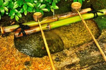 <p>Water purification font beside the stone statue of Buddha</p>