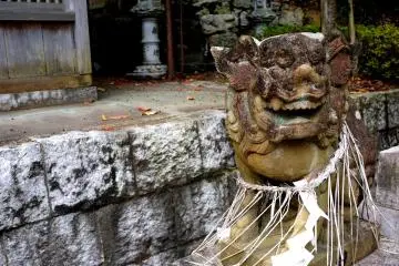 Ancient stone guardian with a necklace of straw rope