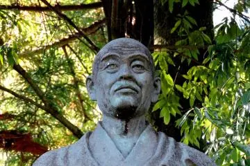 <p>Closer look at the statue of Taicho Daishi in a forested temple</p>