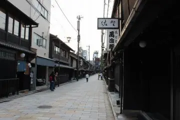 신바시도리. 왼쪽이 기온 거리. 시중의 상가의 경관이 훌륭하다. 거리는 기온 신바시로서 전통적 건조물 보존지구로 지정되어 있어, 그 역사 원래는 지금의 야사카 신사의 몬젠마치로서 헤이안 중기경부터 발전해 카모가와히가시기시의 야마토 대로변에 야사카 신사의 참배객이나 연극객 상대의 찻집 거리가 만들어지게 되어, 그것들은 "기온 소토 로쿠쵸"라고 칭해졌다. 1732년이 되면, 막부보다 정식 찻집 영업의 허가가 나와, 새롭게 모토요시쵸, 하시모토쵸, 린카쵸, 스에요시쵸, 키요모토쵸, 토미나가쵸의 "기온 나이 로쿠쵸"가 개발되게 되었다. 현재의 기온 신바시는, 이 중의 모토요시쵸에 해당한다. 그리고, 에도시대 말기부터 메이지 시대 초기에 걸쳐 최성기를 맞이하여, 에도말기에는 500채나 되는 찻집이 기온에 있었다고 한다