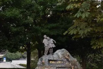 <p>A kid riding past a statue of two kids</p>