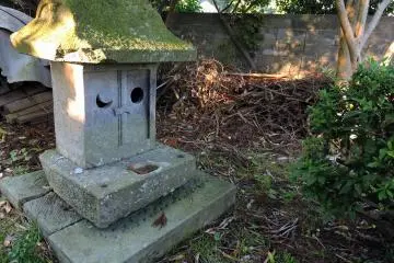 <p>Small moss-covered stone shrine in the corner of the grounds</p>