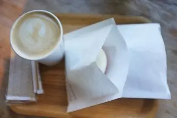 <p>Secangkir cafe latte panas dan donat coklat putih. Bahkan tissue nya juga organik.</p>