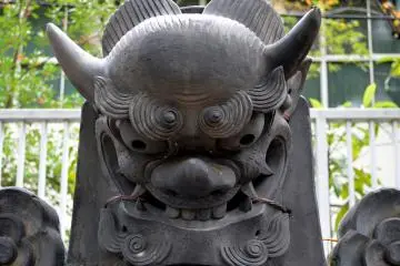 A large Onigawara, a ridge-end roofing tile featuring a devil's face, is displayed in the yard of the temple