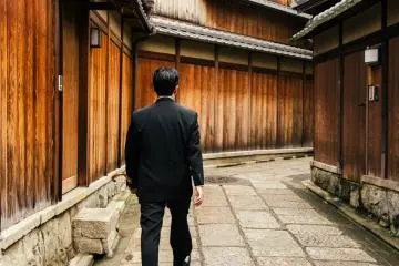 <p>전통 집들 사이로 걸어가던 양복 차림의 신사</p>