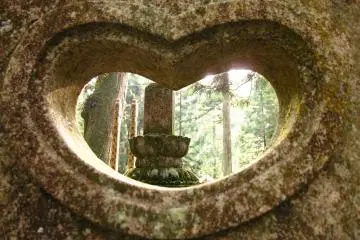 <p>The heart shape of this window could be akin to the shape of a peach or lotus petals, which are frequently used in Buddhist symbology. The carving behind reminds me of a small obelisk jutting out of a flowering lotus.</p>