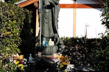 <p>A statue with offerings around its feet</p>