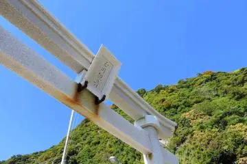<p>White torii gate of Tamagawa Cave Kannon under the clear blue sky</p>