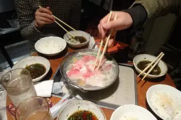 <p>Diners cluster around a pot of Kagoshima's black pork shabu shabu</p>