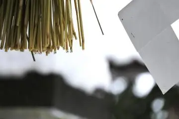 <p>Water droplets on the sacred straw hanging from the stone torii gate</p>