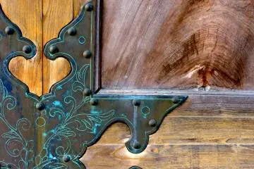 <p>An ornate metal plate protects a corner of one of the doors on the big gate</p>