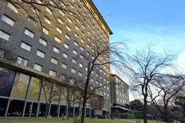 <p>Bare weeping cherry trees in front of Grand Prince Hotel Takanawa which stands opposite the Grand Prince Hotel New Takanawa, with the Japanese Garden in-between</p>