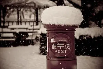 A traditional-style postal box sits beneath a thick layer of snow in the Edo Tokyo Museum.