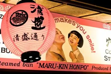 <p>A sign and paper lantern above a shop window</p>