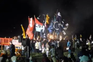 Locals run around a bonfire cheering and chanting.