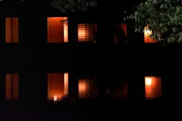 <p>Dimly lit rooms in the Yokokan house reflected on the pond surface</p>